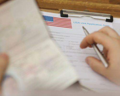Close-up of person filling visa application forms holding personal passport. Standard process to access country. Immigration, permission, embassy concept